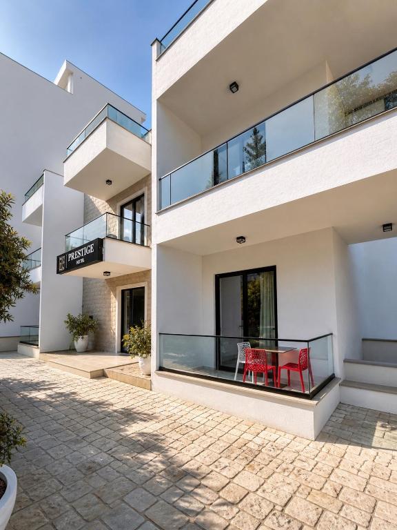 a house with a balcony with red chairs on it at Prestige Hotel in Ksamil