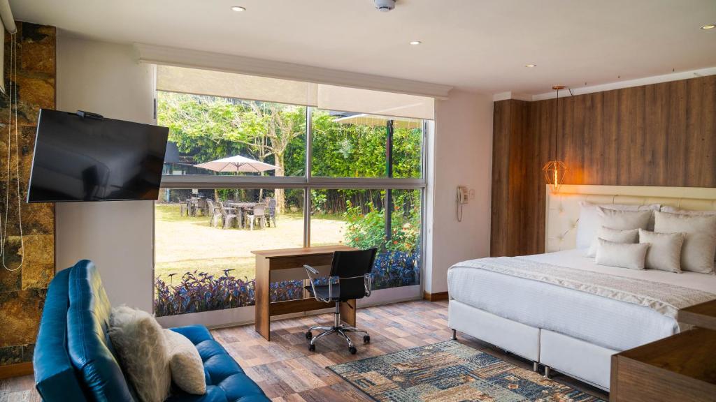 a bedroom with a bed and a desk and a tv at Libertg Hotels Medellin in Copacabana