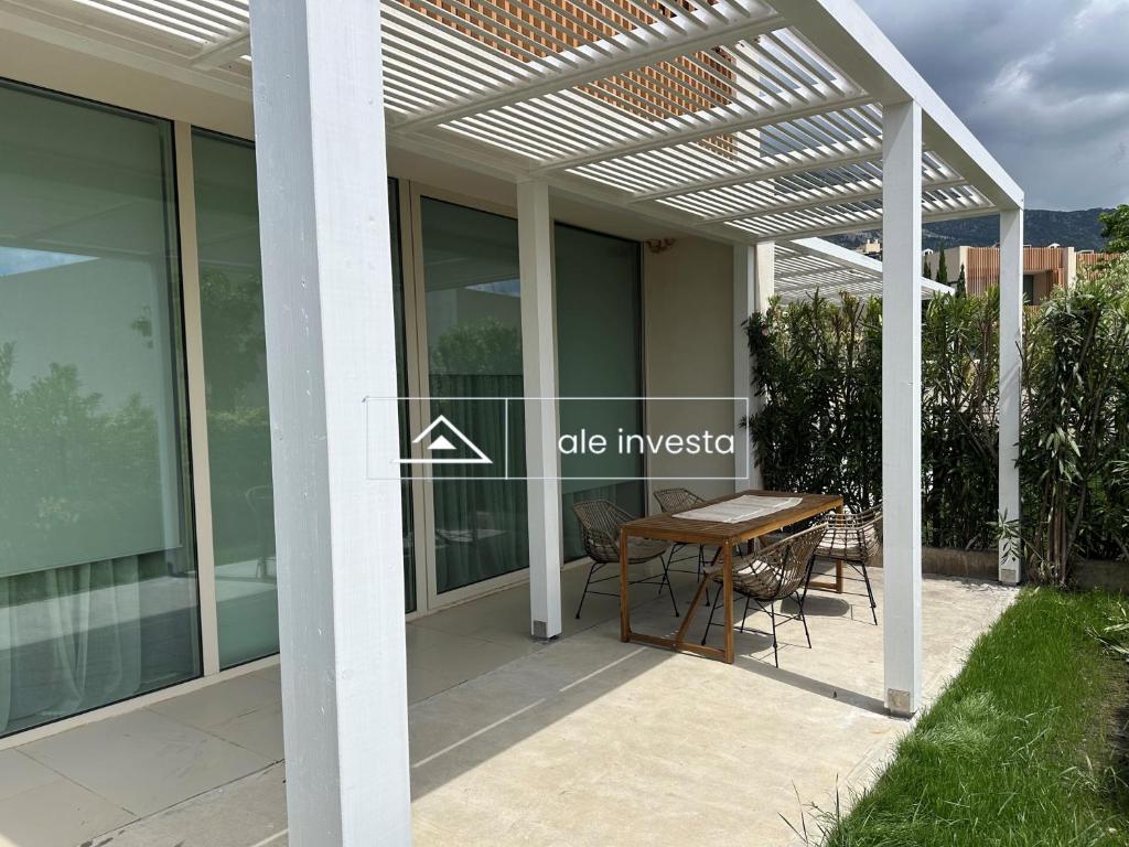 a pergola over a patio with a table and chairs at Green Coast 60b - by Ale Investa in Palasë