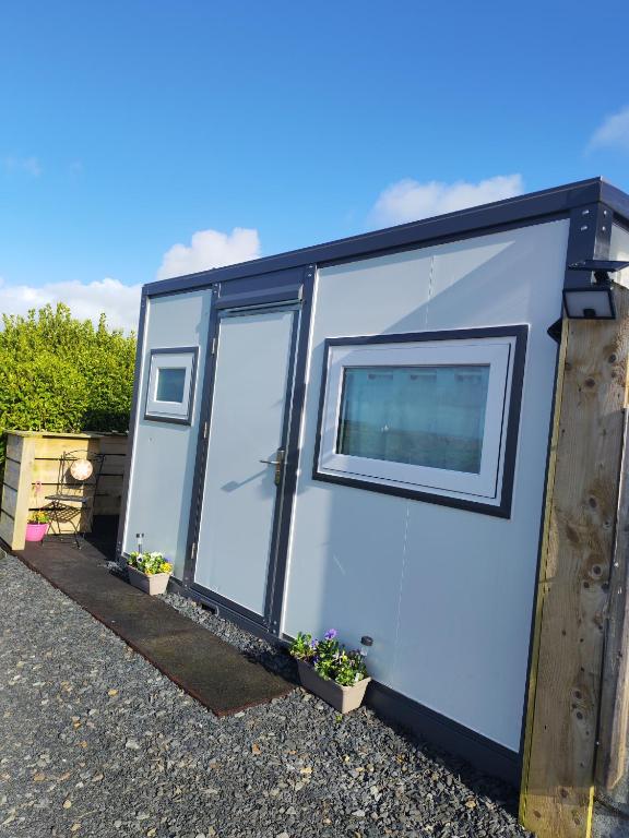 a white trailer with a door and a window at Róisín's Country cabin in Milltown Malbay