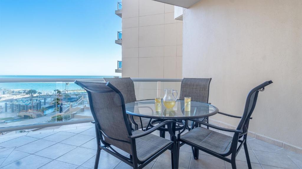 a glass table with two chairs and wine glasses on a balcony at Las Palomas Beach & Golf Resort - One Bedroom Condos in Puerto Peñasco