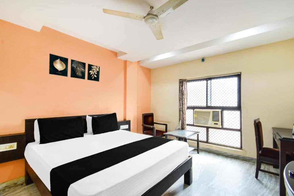 a bedroom with a bed and a desk and a window at Townhouse OAK Secunderabad Near Railway Station Formerly Hotel Brahma in Hyderabad
