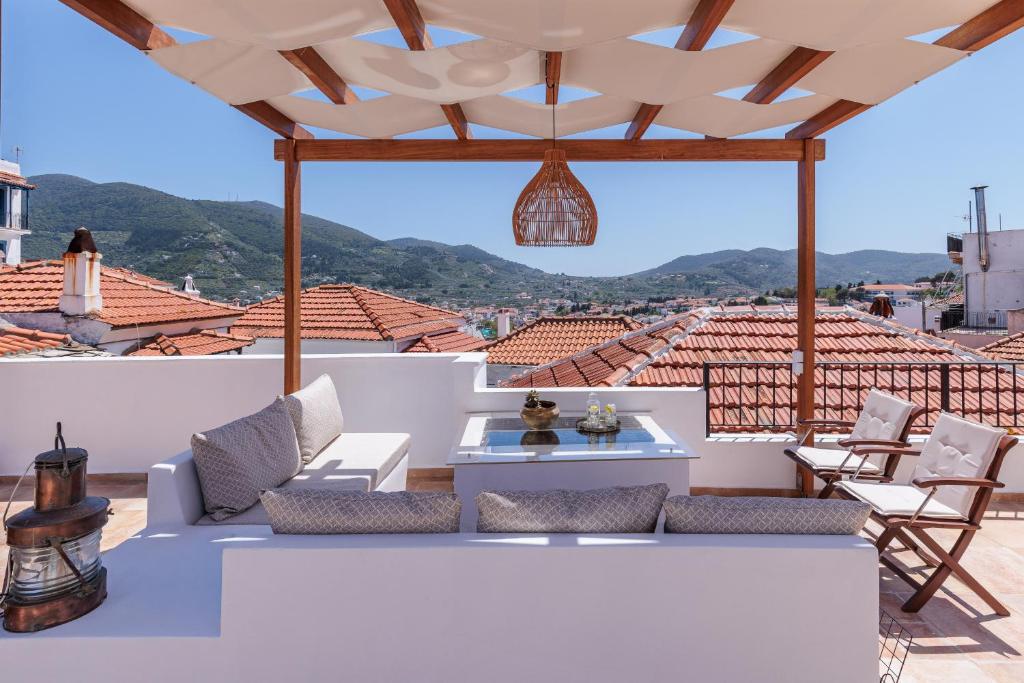 a patio with a couch and chairs on a roof at Manu's House - Refined Design, Effortless Space in Skopelos Town