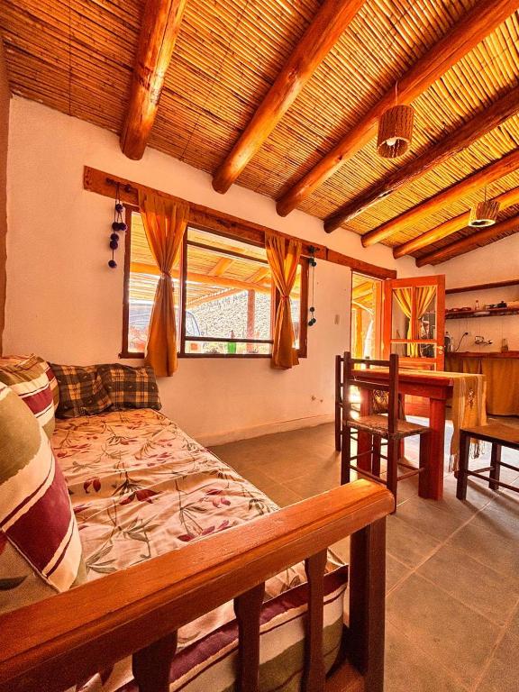 a bedroom with a bed and a desk and windows at Al Pie del Pucara in Tilcara