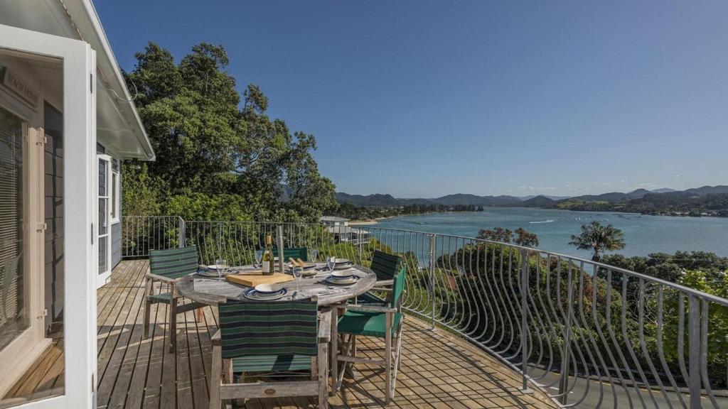 a table on a balcony with a view of a river at The Harbour Masters Cottage for Two in Tairua