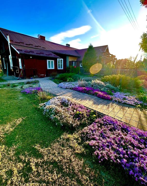 a house with a garden with purple and purple flowers at Dom pod Platanami in Bondyrz
