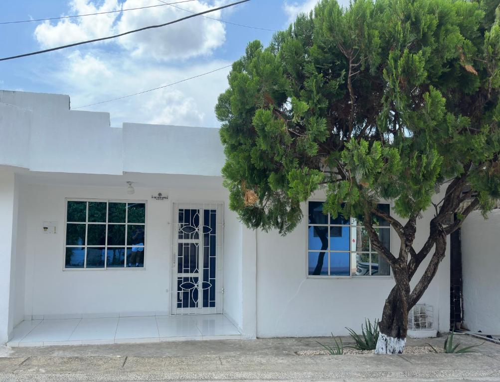 a white house with a tree in front of it at Cabaña linamar in Coveñas
