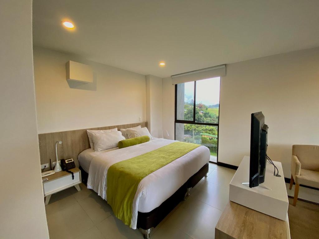 a bedroom with a bed and a television in it at Hotel Rioverde Living Suites in San Antonio de Pereira