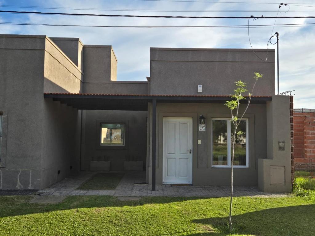 a house with a white door in a yard at Casita Cómoda y Acogedora in Trenque Lauquen