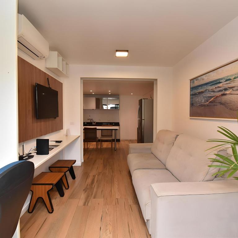 a living room with a white couch and a tv at Metropolitan Flats in Curitiba