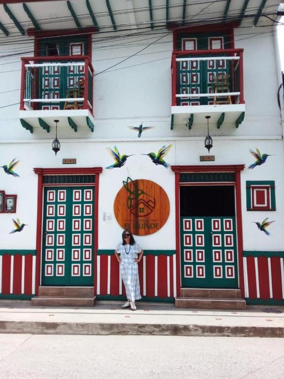 a woman standing in front of a building with birds at Hostal El Quinde in Salento