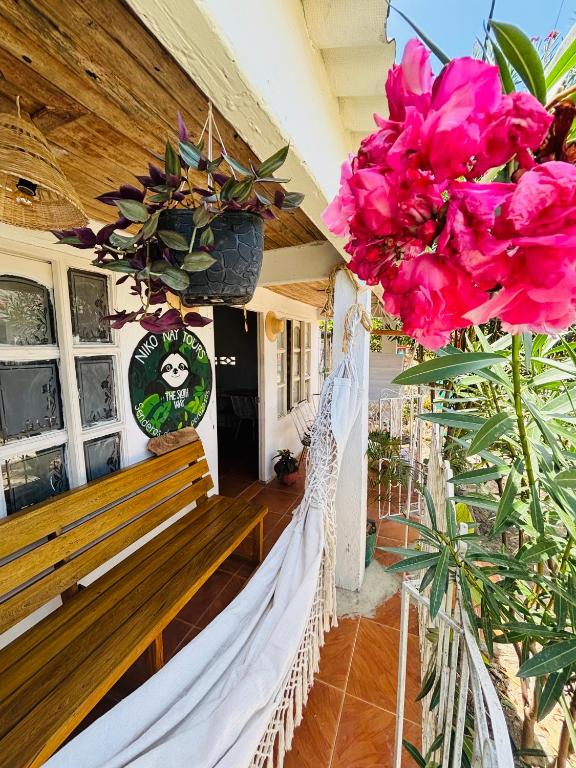 a hammock on the porch of a house with pink flowers at Isla fuerte House in Puerto Limón