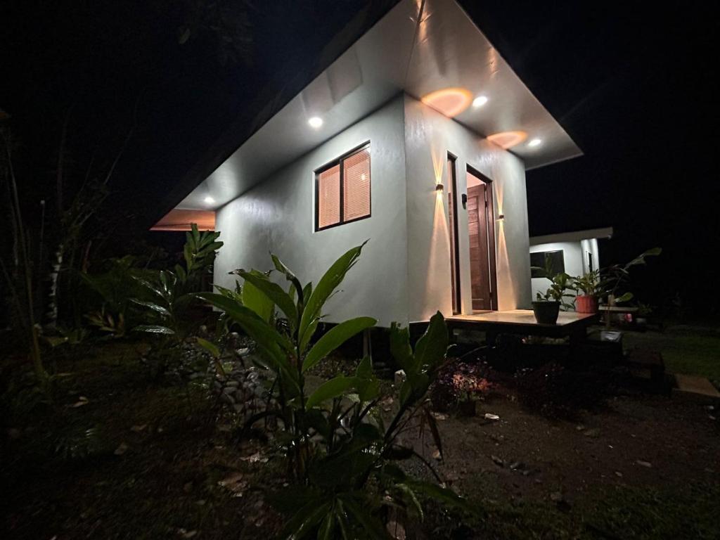 a small white house with a door at night at Bungalows Chachagüita in Fortuna