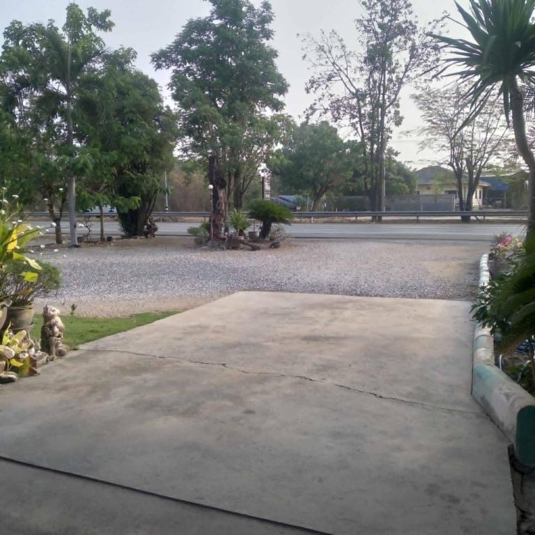 an empty sidewalk in a park with trees and a street at วารินรีสอร์ท in Ban Dong Dam