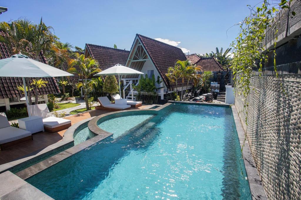 a swimming pool with chairs and umbrellas next to a house at D'Yuki Huts Lembongan in Nusa Lembongan