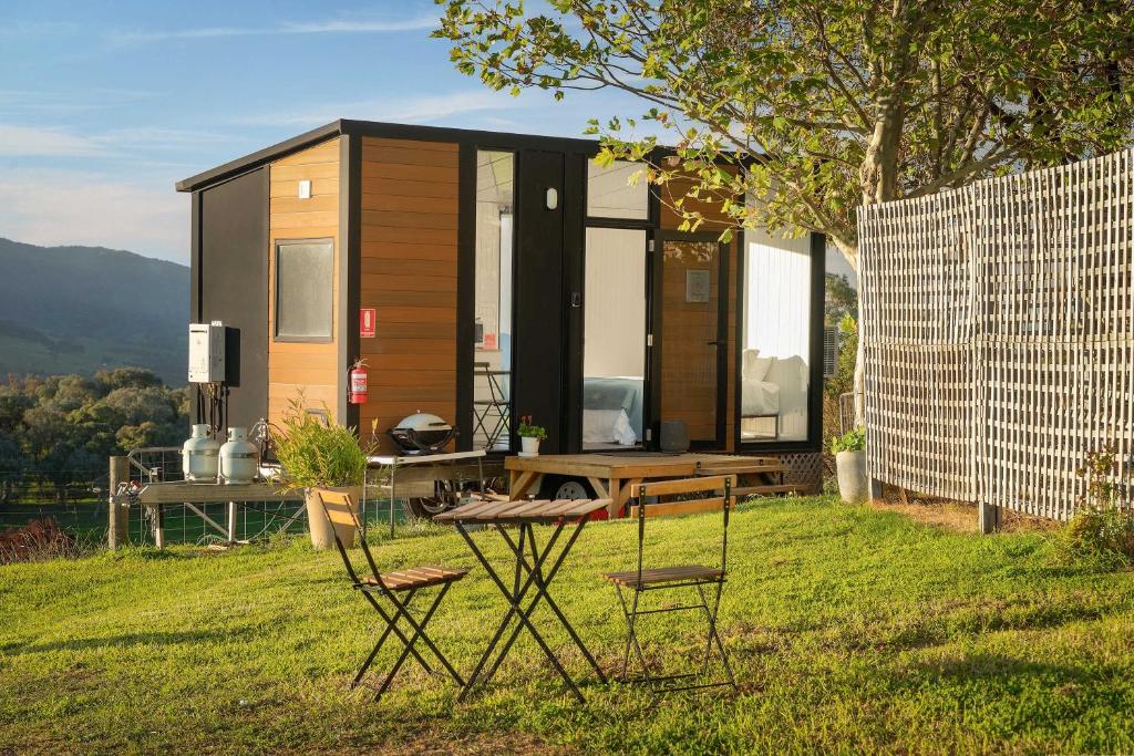a tiny house with a table and chairs in the grass at Nichol Road Hideaway at Annies Retreat by Tiny Away in Yackandandah