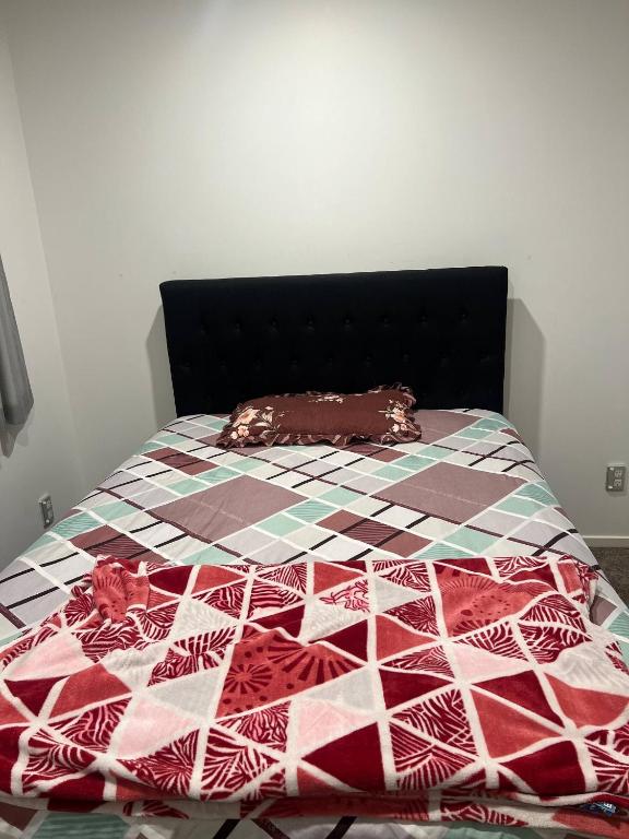a bed with a quilt on top of it at 1 Spacious bedroom available in Auckland