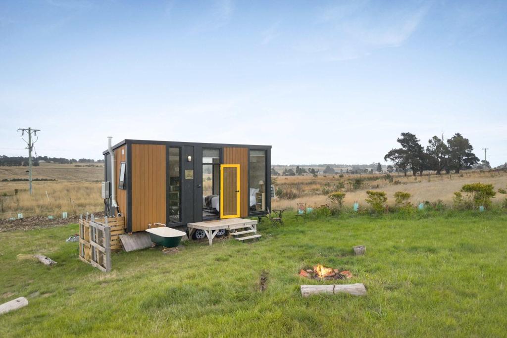 a tiny house in a field with a fire at Tiny Regen Farm Stay by Tiny Away in Lawrence