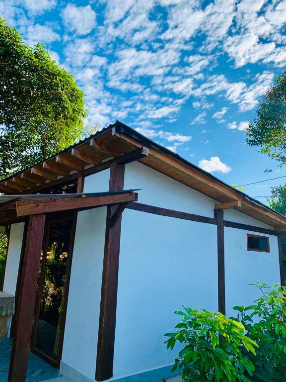 a small white building with a wooden roof at Quirama Lodge Oriente Antioqueño in Carmen de Viboral