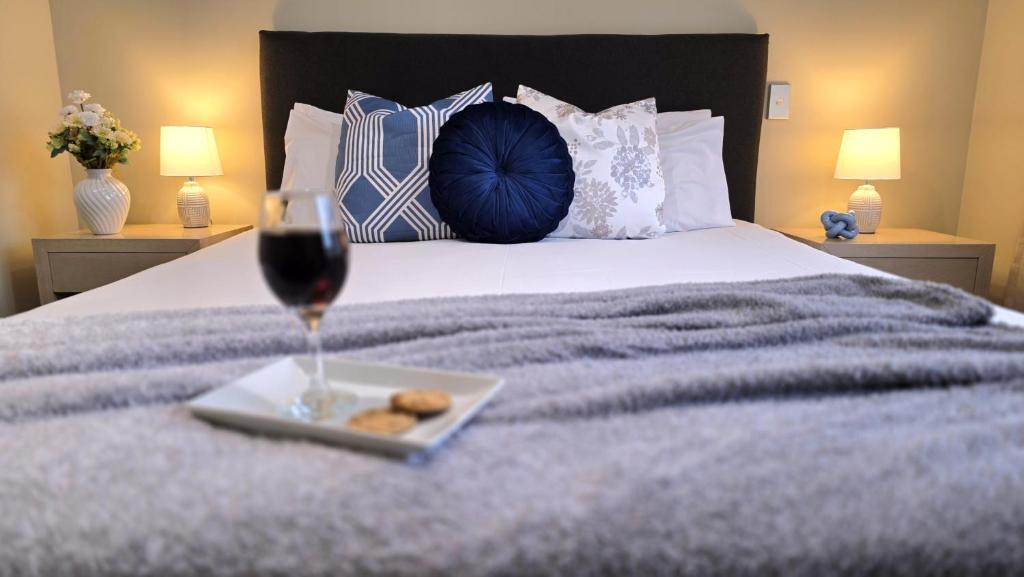 a glass of wine and a plate of food on a bed at TOWER JUNCTION MOTOR LODGE- Motel with Airport and Railway Station Transport Service in Christchurch