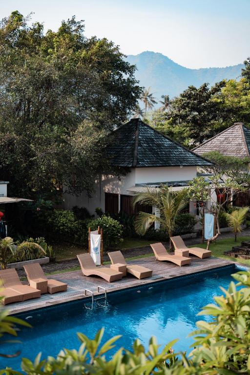 a swimming pool with lounge chairs and a resort at Gunung Agung Timur in Amed