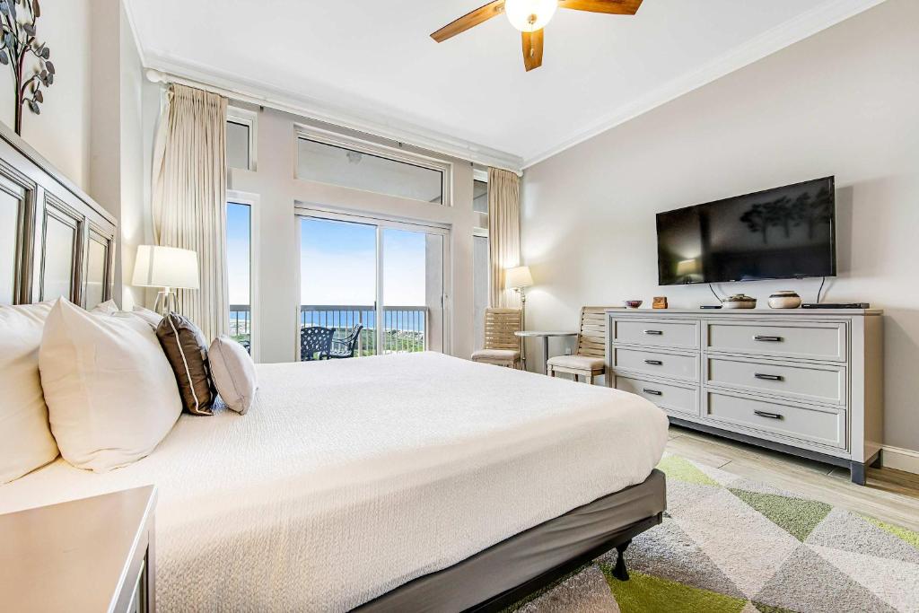 a white bedroom with a large bed and a television at TOPS'L Summit 1108A in Destin