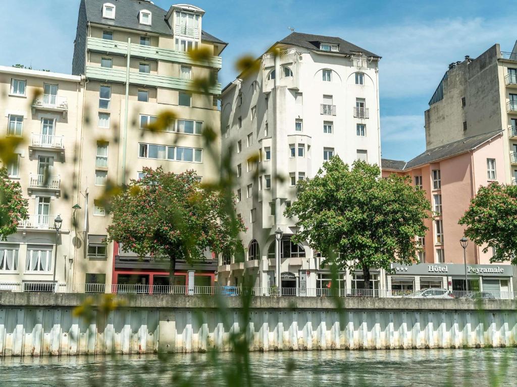 a group of buildings next to a body of water at Hotel Saint Georges Lourdes in Lourdes