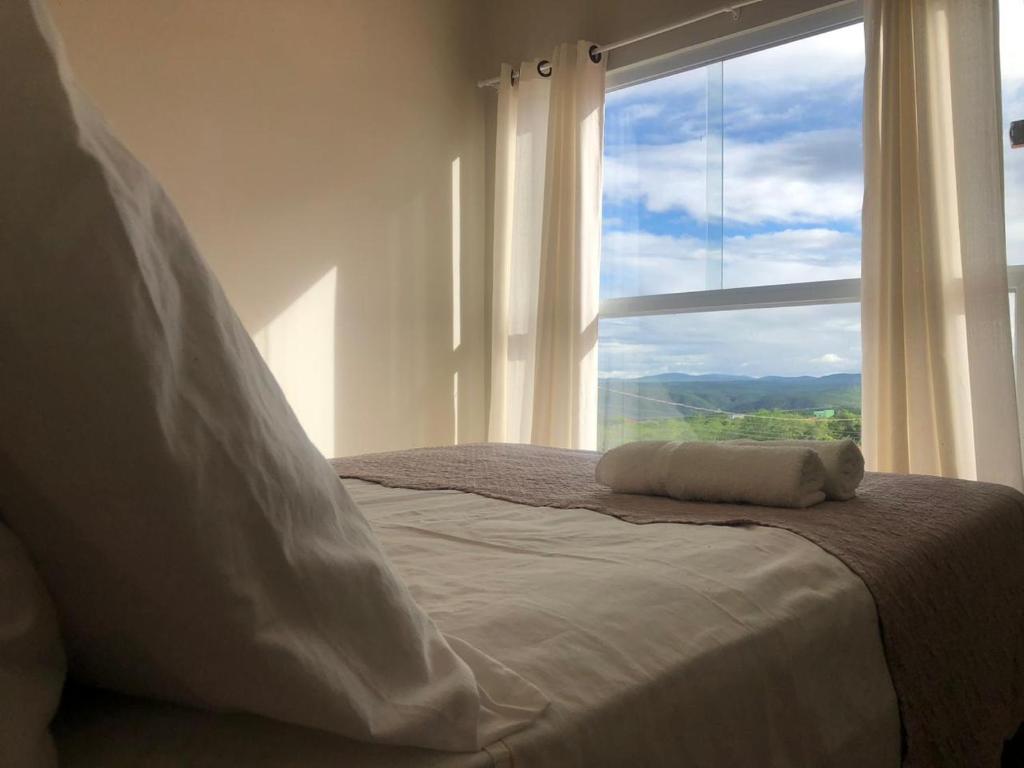 a bed with a pillow on it in front of a window at Pousada Valley House in Piranhas