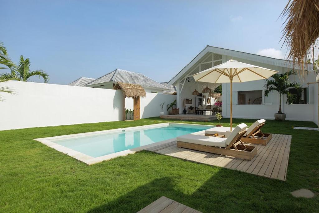 a backyard with a swimming pool and a house at Uluwatu - Beach Villa 5 in Uluwatu