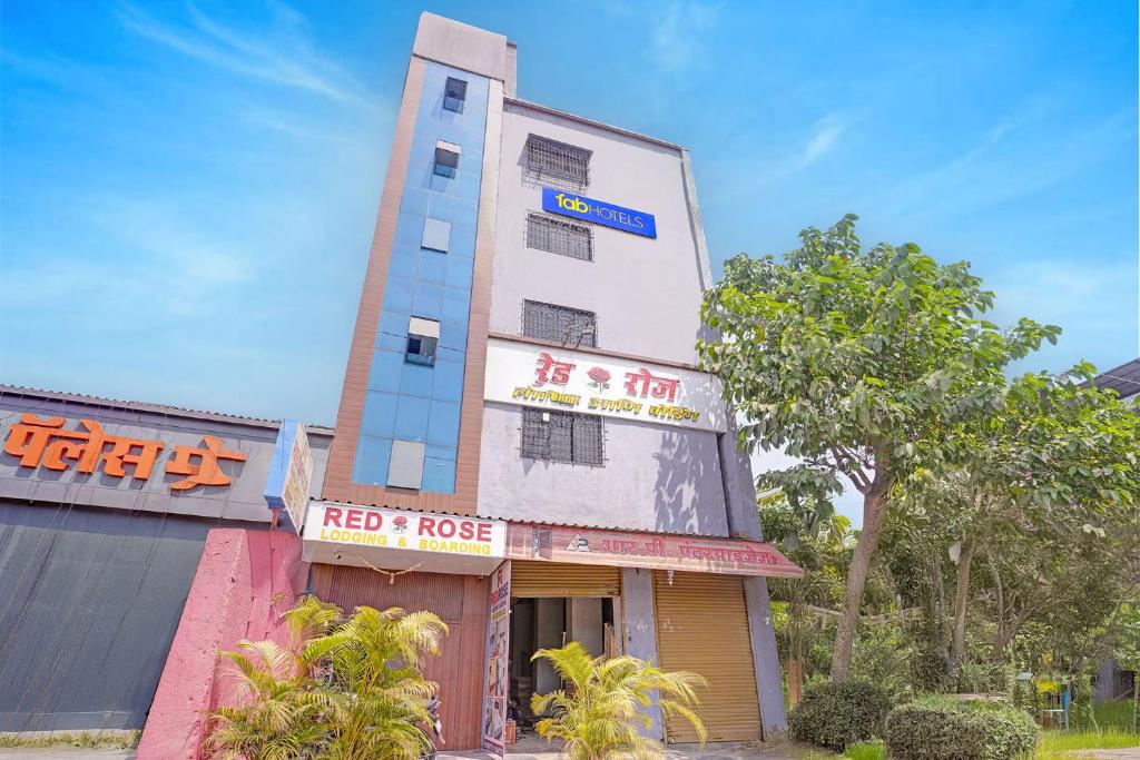 a tall building with a red and house at FabHotel Red Rose Palghar in Nale Sopāra