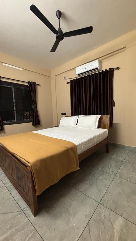 a bedroom with a large bed with a ceiling fan at New Castle Residency in Cochin