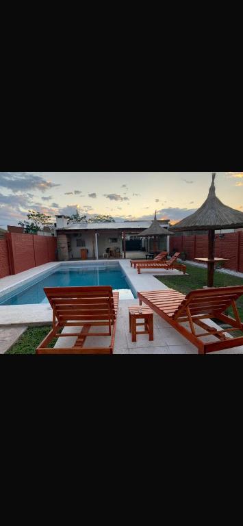 a swimming pool with benches and an umbrella at Cabaña Kuarahy in Empedrado