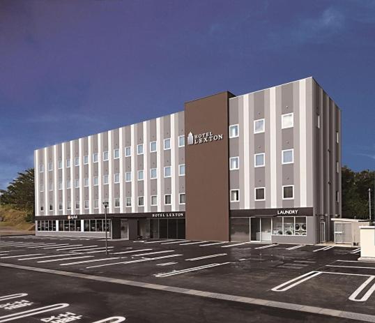 a large building with a parking lot in front of it at Hotel Lexton Tanegashima in Nishinoomote