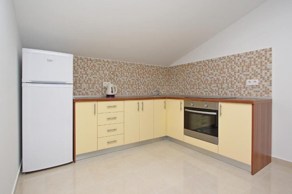 a kitchen with a white refrigerator and cabinets at Apartmani Ruža in Novalja