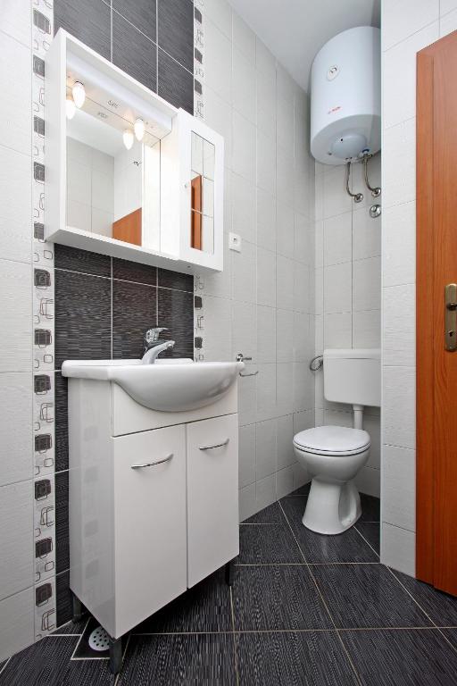 a bathroom with a white sink and a toilet at Apartmani Ruža in Novalja