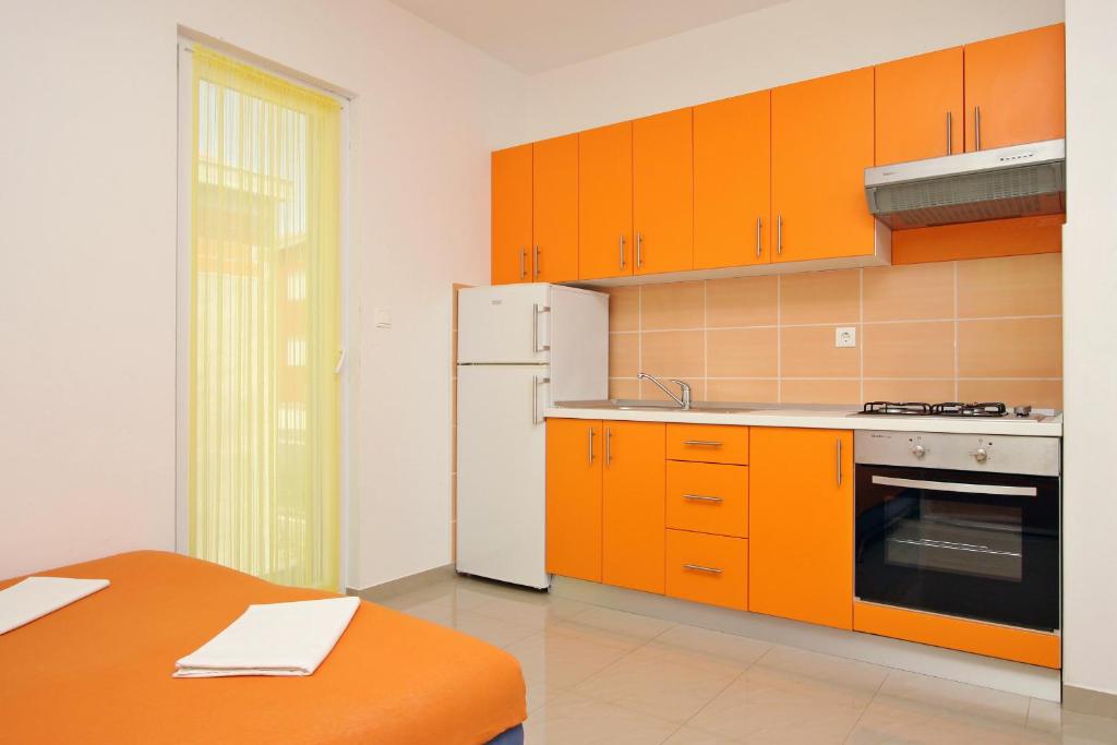 a kitchen with orange cabinets and a white refrigerator at Apartmani Ruža in Novalja