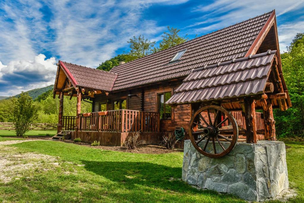 a log cabin with a large wooden wheel in front of it at The Little Mountain Cabin in Borlova