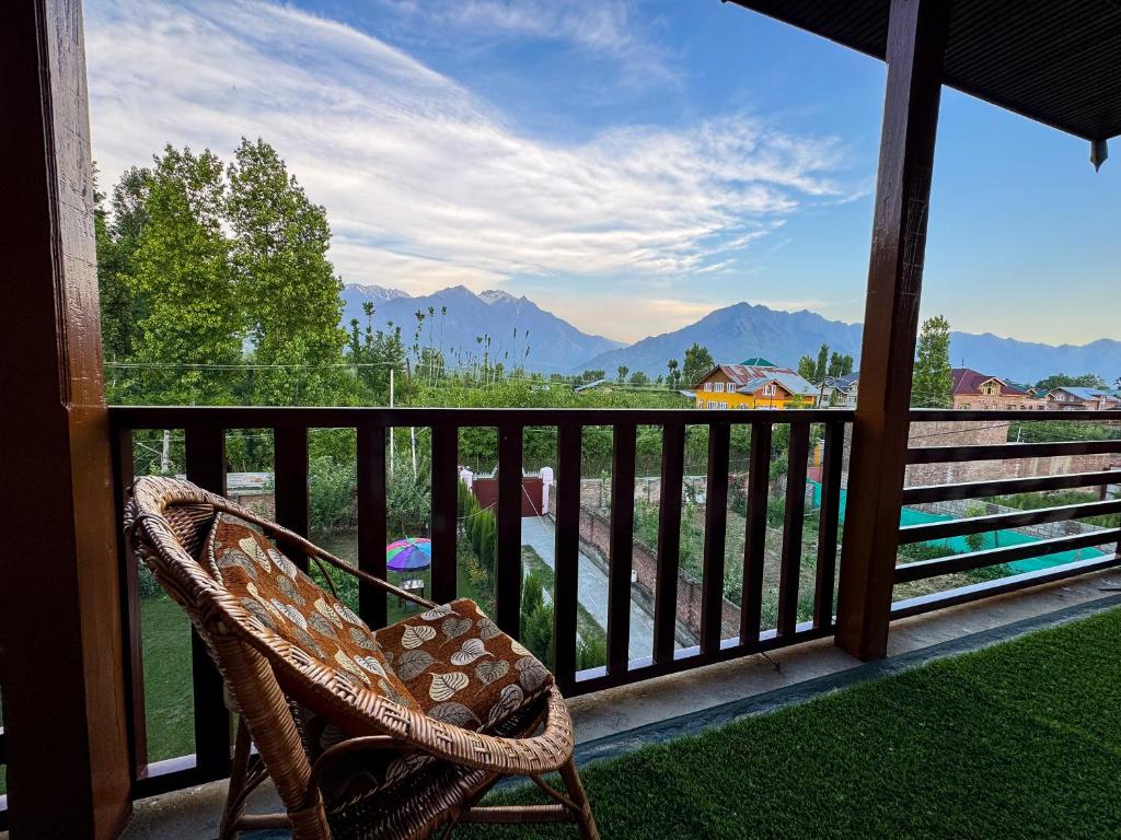 a wicker chair sitting on a porch with a view of mountains at The Other House Srinagar in Srinagar