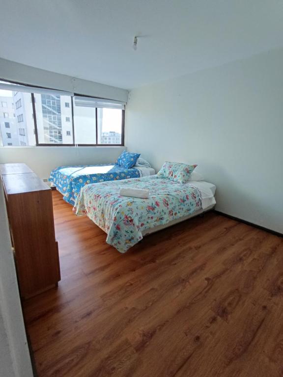 a bedroom with two beds and a wooden floor at Alojamiento Centro Osorno Plaza del Toro in Osorno