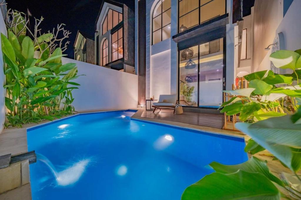 a large blue swimming pool with plants around it at 2BR villa w- pool & beach access in Mengwi