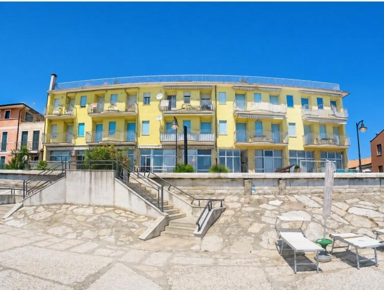 a yellow building with stairs in front of it at President Frontemare - Agenzia Cocal in Caorle