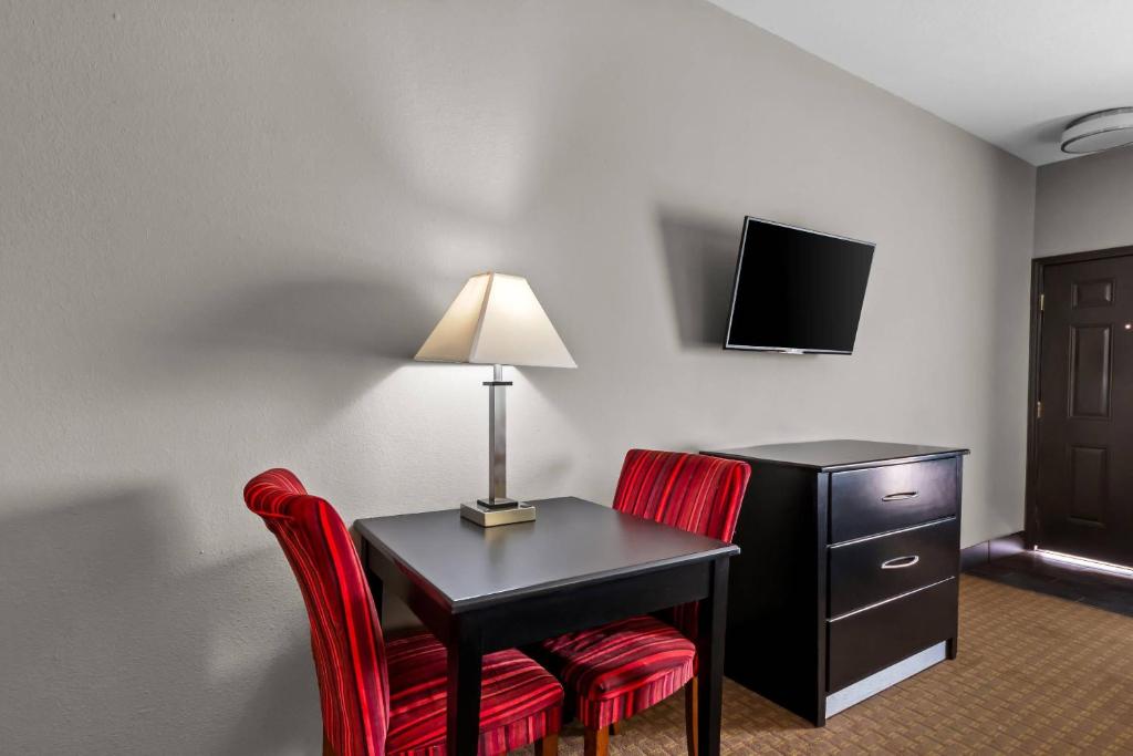 a hotel room with a desk with two chairs and a lamp at Rodeway Inn in Dilley