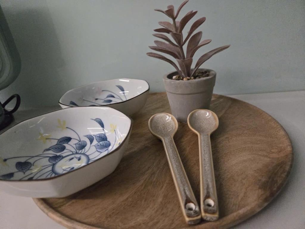 two spoons and a potted plant on a wooden tray at Bống's Homesray and café in Ho Chi Minh City