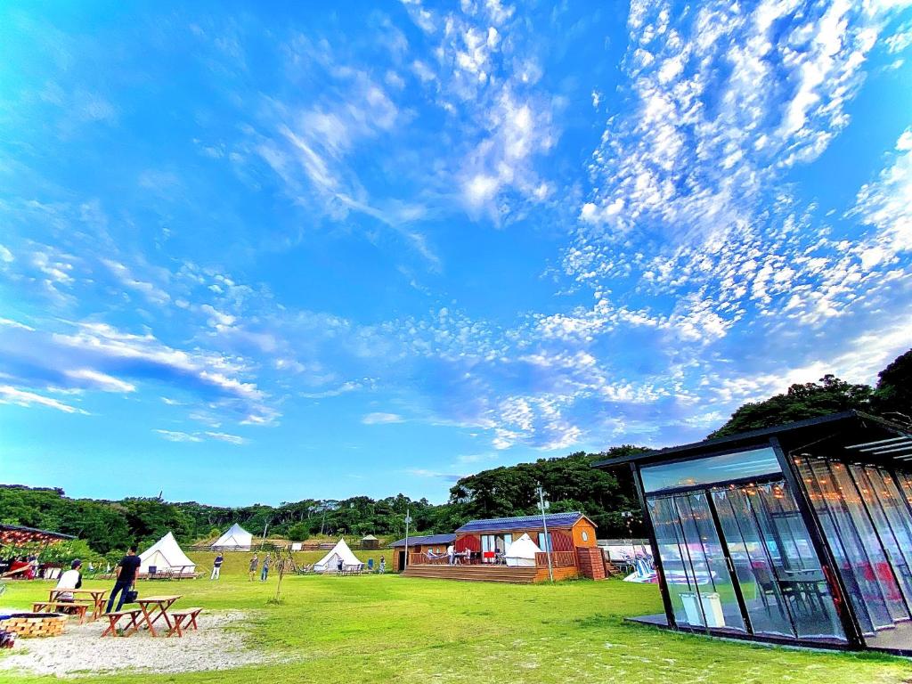 a group of tents in a field with a cloudy sky at Kabuku Resort in Shima