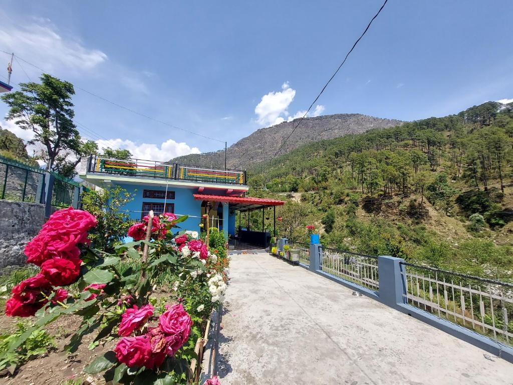 a blue building with flowers in front of it at PeaceVibe Homestay in Uttarkāshi