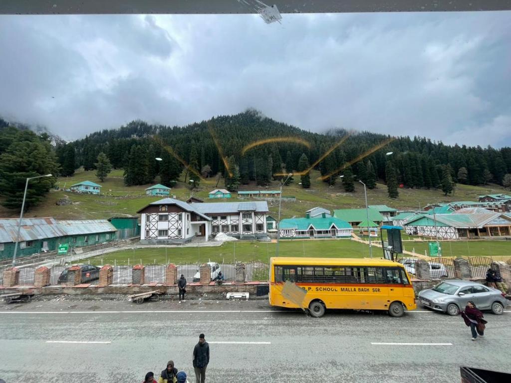 a yellow bus is parked in a parking lot at Hotel Sounsar and Restaurant in Sonāmarg