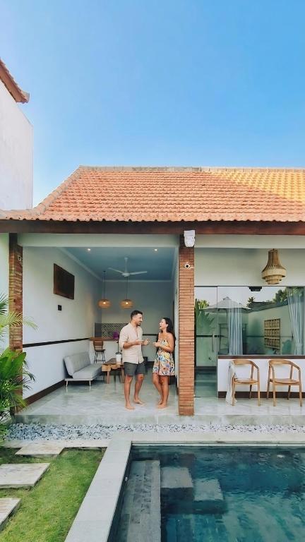 two people standing next to a house with a swimming pool at Sejati Villas - Petitenget in Seminyak