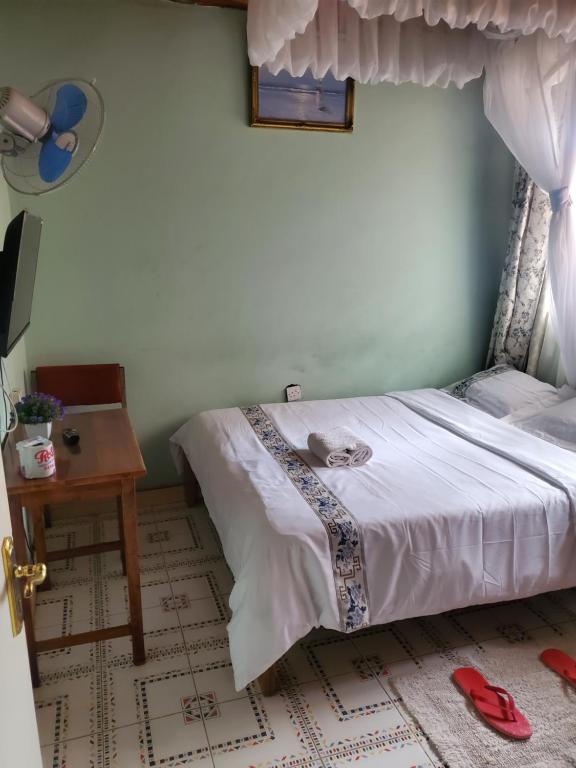 a bedroom with a bed and a table and a window at Torchys in Kisumu