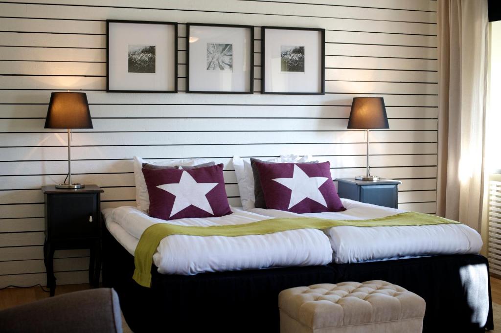 Schlafzimmer mit einem Bett mit lila und weißen Kissen in der Unterkunft Hotell Tinget in Sala