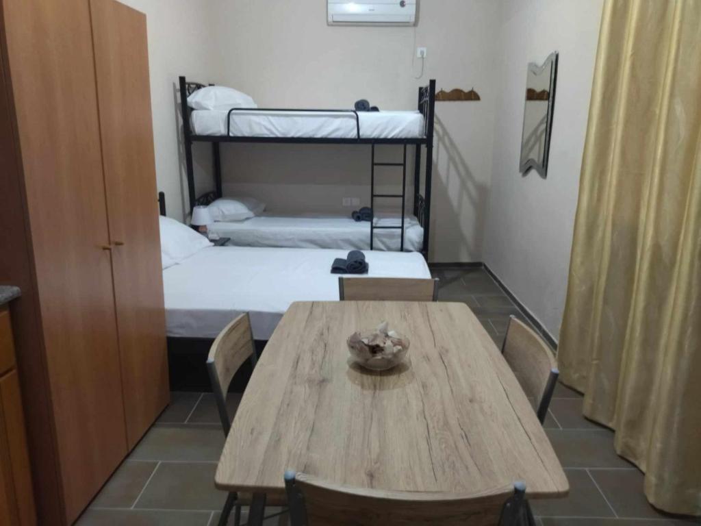 a room with a wooden table and two bunk beds at Mani GuestHouse in Kyparissos
